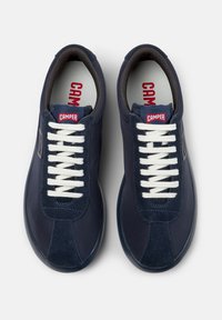 Sneakers blu navy con lacci bianchi, tomaia in pelle liscia e texture sottile, con il logo rosso "CAMPER" sulla linguetta.