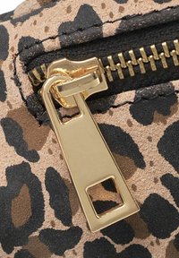 Tessuto con stampa leopardata, con una zip dorata e denti neri, che mette in risalto una superficie testurizzata e motivi contrastanti.