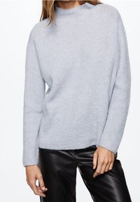 Maglione a coste di un delicato blu chiaro con collo alto e maniche lunghe, realizzato in un morbido materiale testurizzato. Abbinato a pantaloni neri.