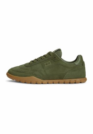 Olive green suede sneaker with brown rubber sole, lace-up design, and subtle stitched detailing along the side and heel.