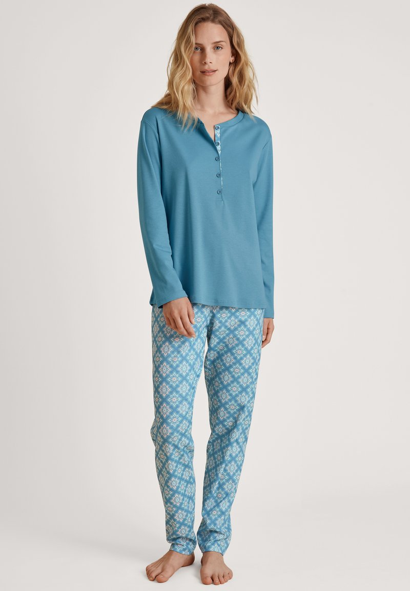 Langsleeve teal shirt met een knopenlijst, gecombineerd met lichtblauwe pyjamabroek met een patroon van bloemen. Zacht, lichtgewicht stof.