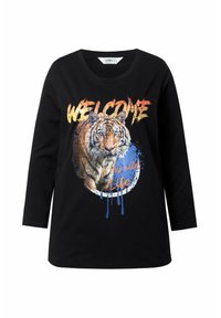 Camiseta de manga larga negra con un estampado gráfico de tigre que incluye el texto "BIENVENIDO" y salpicaduras de colores. Fabricada con un tejido suave y elástico.