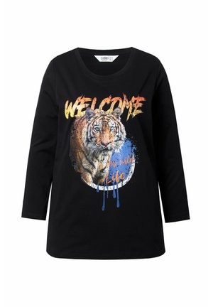 Camiseta de manga larga negra con un estampado gráfico de tigre que incluye el texto "BIENVENIDO" y salpicaduras de colores. Fabricada con un tejido suave y elástico.