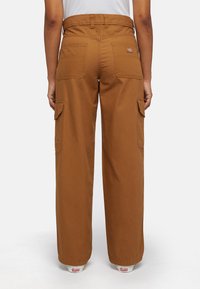 Brown cotton cargo pants with a high waist, wide legs, two back pockets, and side pockets, featuring a small logo tag on the waistband.