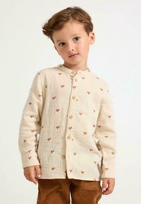 Cotton cream-colored shirt with light brown fox patterns, button closure, and long sleeves, paired with corduroy brown pants.
