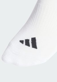 Biała sportowa skarpetka z prążkowaną fakturą i czarnym logo z trzema ukośnymi paskami w okolicy palców.