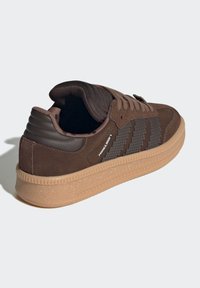 Brauner Sneaker aus strukturiertem Wildleder und synthetischen Überzügen. Ausgestattet mit braunen Schnürsenkeln, gepolstertem Schuhkragen und einer Gummisohle mit einem gemusterten Design.