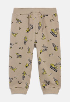 Pantaloni color sabbia con elastico in vita e coulisse. Presentano motivi di veicoli da costruzione gialli e coni stradali. Tessuto dalla texture morbida.