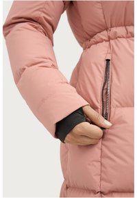 Pufferjack in lichtroze stof met een tailleriem. Beschikt over een zwarte ritszak en elastische manchetten voor een strakke pasvorm. Logo geperst op de mouw.