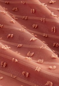 Tissu rose clair avec un motif floral brodé texturé et de fines rayures horizontales, créant une apparence douce et délicate.
