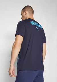 Tumši zilas krāsas īsām piedurknēm t-krekls ar apaļu dekoltē, aizmugurē ar tirkīza krāsas "CITYZEN" tekstu un logotipu, izgatavots no mīksta kokvilnas materiāla.