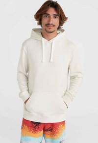 Cream hoodie with drawstrings and a front pocket, features a light blue logo on the chest, paired with multicolored patterned shorts.
