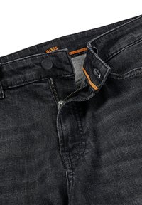 Svarta jeans i denim med dragkedja och knappstängning. Har orange accentstickning och en svart etikett i midjan.