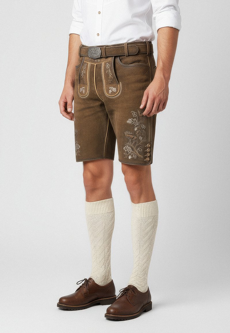 Bruna läderhosen med blommig broderi, bältesslingor, framfickor och sidoknappar. Bärs med krämfärgade knästrumpor och bruna skor.