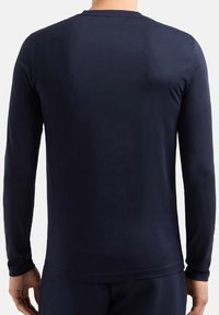 Maglietta a maniche lunghe blu navy realizzata in tessuto morbido, con colletto a girocollo. Design aderente con maniche slim e orlo dritto.