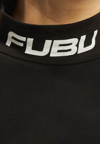 Čierne bavlnené tričko s vysokým golierom, na ktorom je biele logo "FUBU". Hladká, priliehavá textúra s jemným ribovaním pozdĺž goliera.
