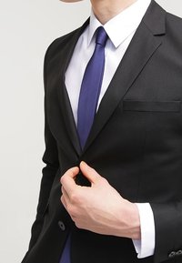 Completo nero su misura con un dettaglio a tasca singola, camicia bianca e cravatta viola uniforme. Tessuto morbido, design aderente.