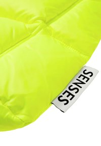 Bright neon yellow padded fabric with a smooth texture, featuring a label with "SENSES" in black on a white background.