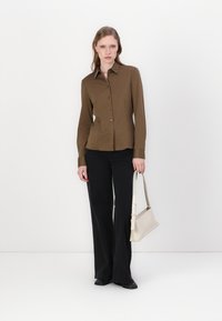 Brown button-up shirt with long sleeves, black flared pants, and a light beige handbag. Smooth fabric with a structured fit.