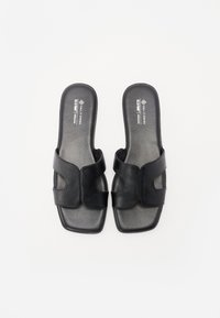 Sandales à glissière en cuir végétalien noir avec deux larges sangles, un bout carré et une texture lisse. Design minimaliste avec des accents découpés subtils.