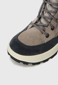 Grå semsket og mørkeblå skinn sneaker med teksturert yttersåle, grå lisser og forsterkede snøringer. Har rund tå og sydd detaljer.