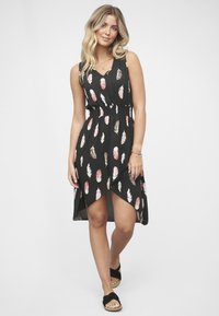 Czarna sukienka z dekoltem w serek, bez rękawów, z marszczonym paskiem w talii oraz wzorem z piór w kolorze różowym i kremowym. Asymetryczny dół dodaje charakteru.