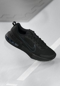 Crna atletska tenisica s mrežastim gornjim dijelom, gumeni potplat, vidljiva Air Max amortizacija i suptilni logotipski naglasci. Standardni dizajn s vezanjem.