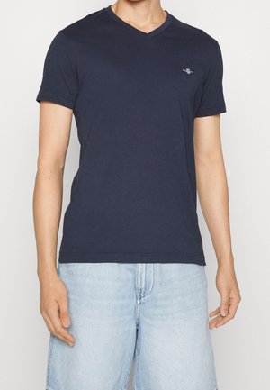 Marineblaues Baumwoll-T-Shirt mit V-Ausschnitt, kurzen Ärmeln und einem kleinen gestickten Logo auf der Brust; weiche Struktur und reguläre Passform.