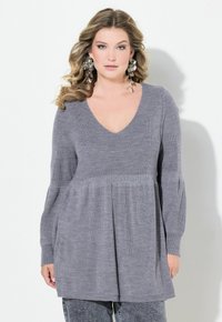 Pull en tricot gris avec un col en V, des manches longues et un ourlet évasé. Texture douce avec des côtes verticales et des poches latérales.