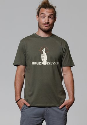 Olijfgroene katoenen T-shirt met een afbeelding van een hand met gekruiste vingers en stralen erboven, met de tekst "FINGERS CROSSED" eronder.