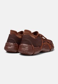 Brown sneakers with a textured mesh upper, elastic lace system, and a distinctive rubber sole featuring a molded design.