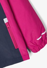 Kurtka s blokováním barev, která má magentovou horní část a námořnickou spodní část. Elastické manžety a boční zipová kapsa v odpovídající magentové barvě. Hladký povrch.