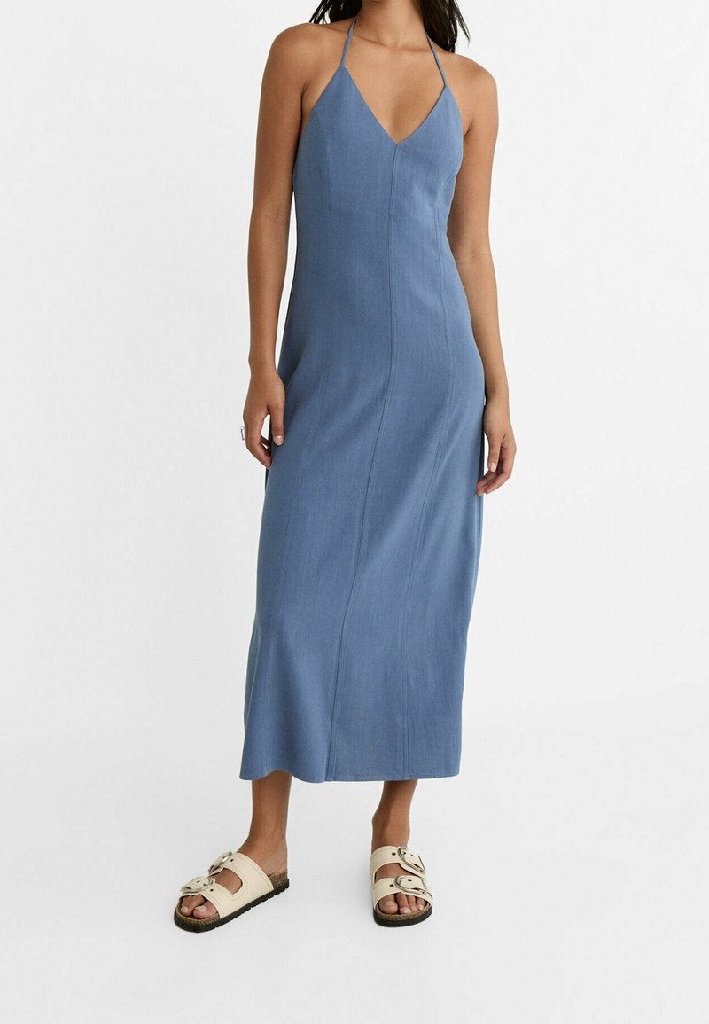 Robe maxi bleue avec un décolleté en V et des bretelles spaghetti, fabriquée en tissu léger. Associée à des sandales à enfiler couleur crème avec un détail de boucle.