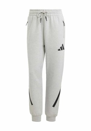 Pantalones de chándal gris claro con cintura elástica, cordón, dos bolsillos laterales con cremallera y rayas y logotipo negros. Material suave de mezcla de algodón.
