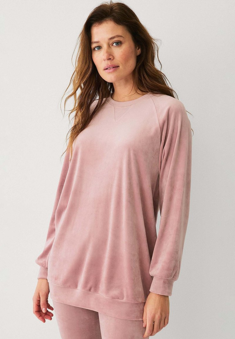 Roze velours sweatshirt met lange mouwen, geribbelde manchetten en een ronde hals. Zachte textuur en ontspannen pasvorm, gestyled met bijpassende onderkleding.