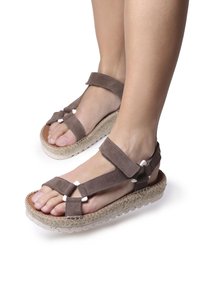 Bruna mockaskinnsandaler med cremefärgade detaljer, justerbara remmar och en vävd jutesula. Lätt upphöjd, öppen tå-design.