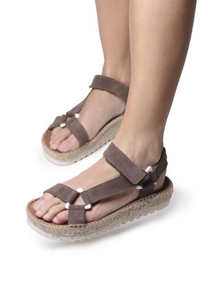 Bruna mockaskinnsandaler med cremefärgade detaljer, justerbara remmar och en vävd jutesula. Lätt upphöjd, öppen tå-design.