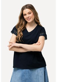 Camiseta de manga corta de color azul marino con escote en V, que presenta adornos de encaje en las mangas. La tela parece suave con un corte holgado.