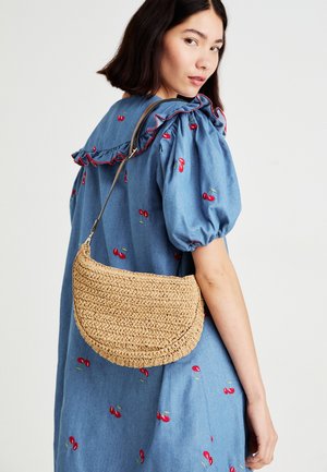 Vævet strå crossbody taske i en halvmåneform, der har en glat overflade og en neutral beige farve, suppleret med en metalskyder.