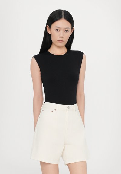 Μαύρο αμάνικο κορμάκι σετ με ψηλόμεσο λευκό σορτς που διαθέτει μπροστινές τσέπες και μεταλλικές λεπτομέρειες με κουμπιά. Ομαλή υφή υφάσματος.