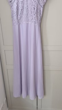 Vestido de lavanda con una parte superior de encaje que presenta un patrón floral, tejido fluido y diseño hasta la rodilla, con una sutil textura y detalles.