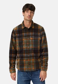 Chemise en flanelle présentant un motif à carreaux en vert foncé, noir et orange. Elle a un devant à boutons et des manches longues. Texture douce.