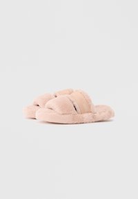 Lækre lyserøde hjemmesko med krydset remme i beige stof. Blød tekstur med tykke såler for komfort. Rund form og fluffy design.