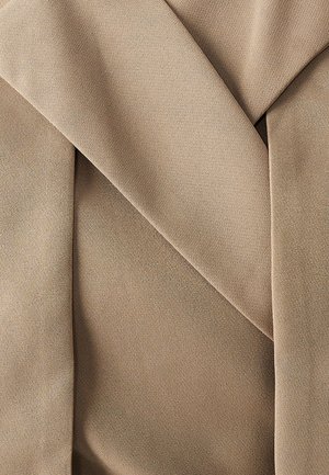 Tissu beige au toucher lisse, avec des sections pliées créant un design en couches. La couleur est uniforme, sans motifs.