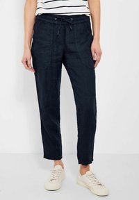 Granatowe spodnie z mieszanki lnu z elastycznym pasem, sznurkiem do regulacji i bocznymi kieszeniami. Posiadają zwężaną nogawkę i luźny krój.