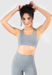 Szary biustonosz sportowy i pasujące legginsy wysokiej talii wykonane z elastycznego materiału. Charakteryzują się okrągłym dekoltem i elastycznym paskiem na dole.