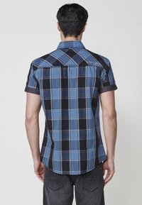 Korte mouwen geruit shirt in blauw en zwart, met contrasterende ruitenpatronen, een klassieke kraag en opgerolde mouwen. Achteraanzicht toont logo-detail.