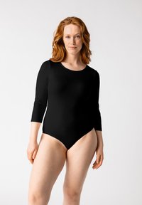 Bodysuit negro de manga larga con escote tipo barco, hecho de una tela suave y elástica. Diseño ajustado con una abertura de pierna alta.