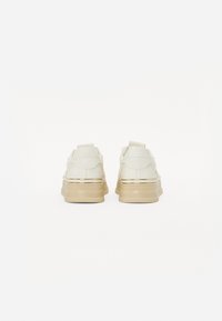 Baskets plateforme en blanc cassé avec des accents dorés ; dessus en synthétique lisse, col rembourré et semelle épaisse beige.