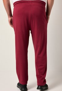 Bordeauxfarbene Baumwoll-Sweatpants mit elastischem Bund, geradem Beinanschnitt und Seitentaschen. Leicht, mit glatter Textur, geeignet für legere Outfits.